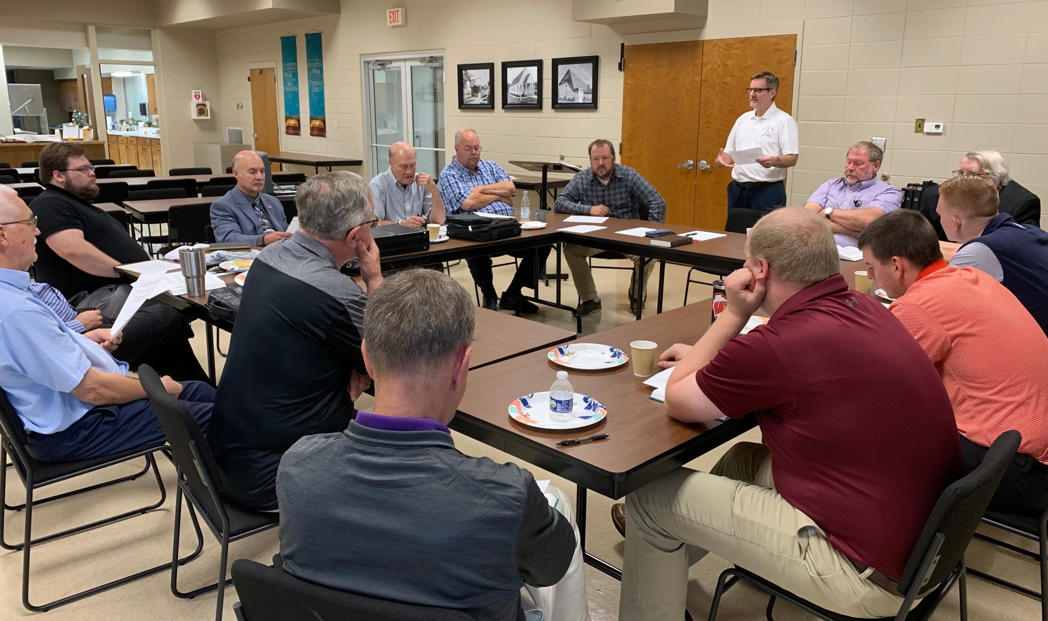 Congregation leadership meeting — men gathered around tables for discussion